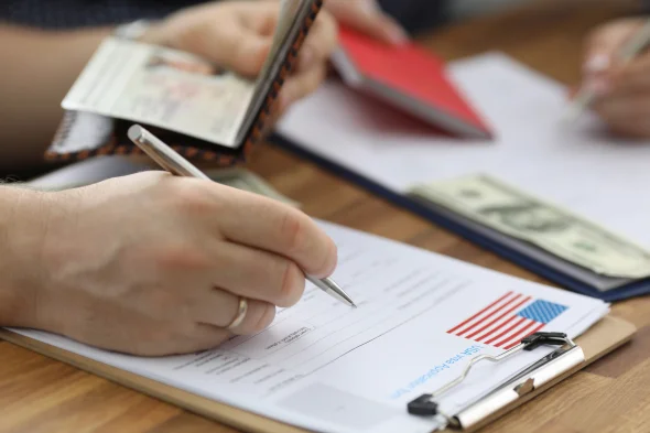 An hourglass next to U.S. dollar bills, symbolizing time and money.