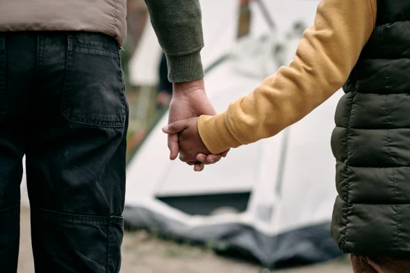 Holding Hand of a Child Against Migrant Camp