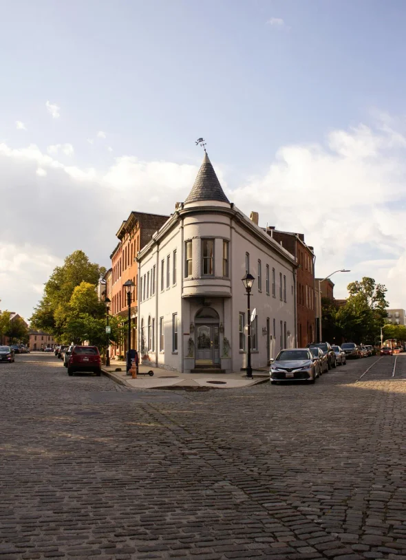 Historic street with cobblestone roads and a turret-roof building.